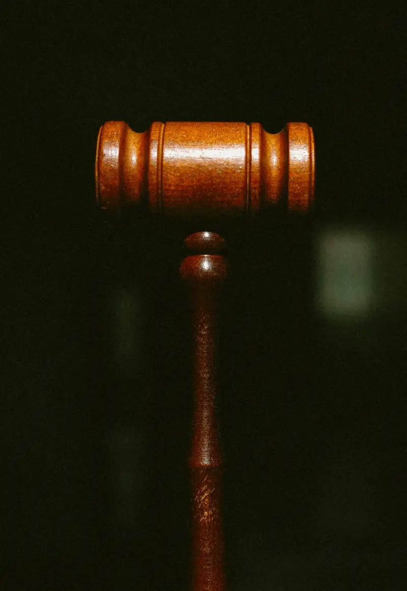 Wooden gavel lit against a dark background, symbolising judicial outcomes